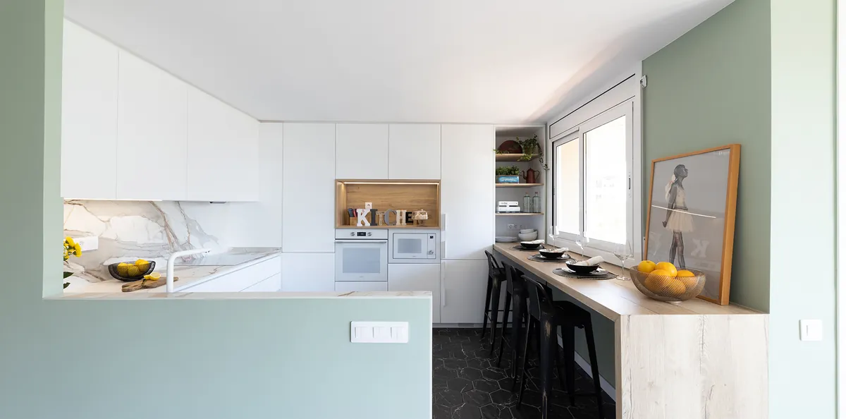 Cocina reformada en blanco con pared verde agua y barra